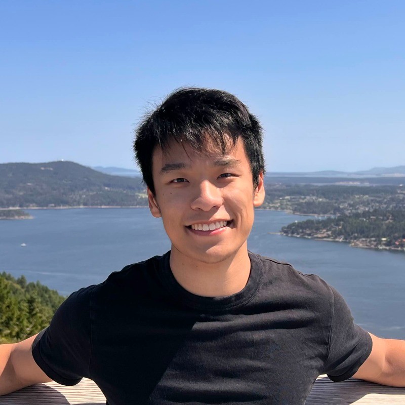 Edward Zhu smiling on a lookout above the water
